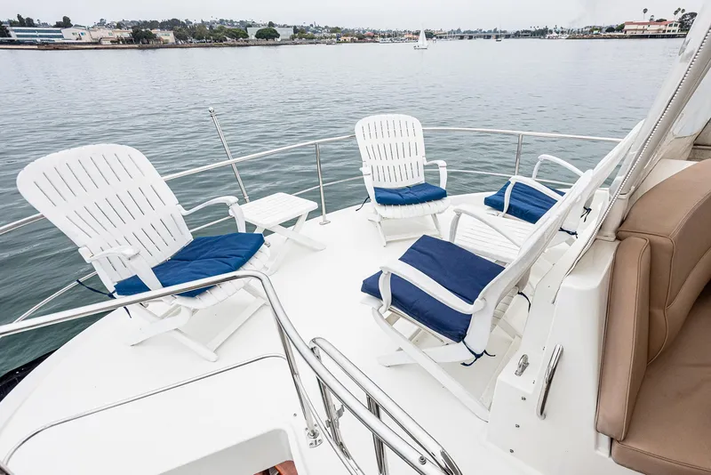Slide: The Image of 2005 Carver 560 Voyager yacht deck with white chairs and blue cushions. - 22