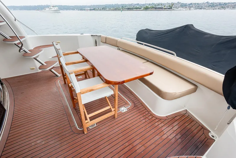 Slide: The Image of 2005 Carver 560 Voyager yacht deck with wooden table and chairs, overlooking serene waters. - 26