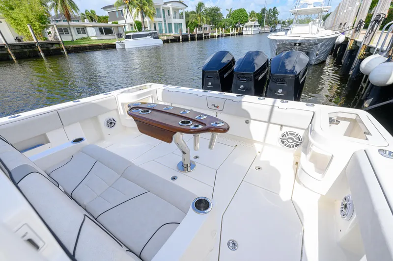 Slide: The Image of 2023 SeaVee 420Z boat with spacious deck and triple outboard engines docked by waterfront homes. - 15