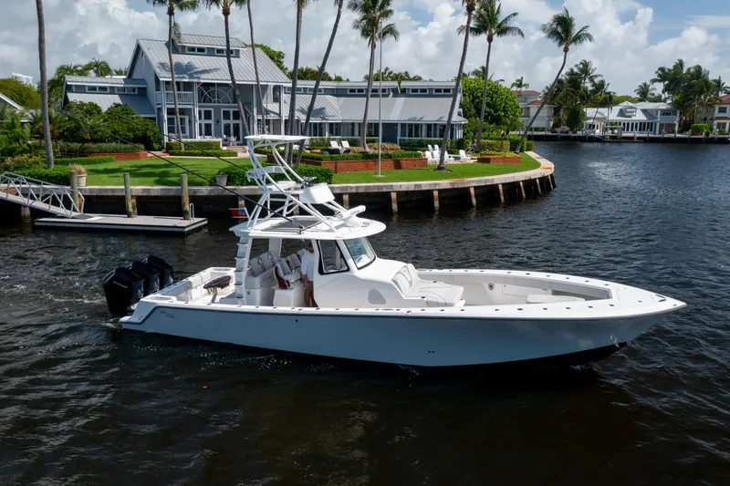 Slide: The Image of 2023 SeaVee 420Z boat cruising on a scenic waterfront near luxury homes. - 2