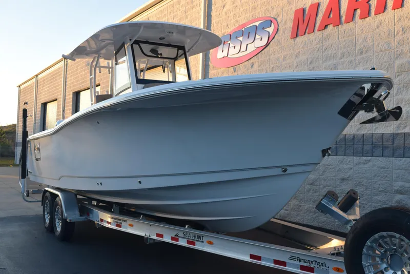 Slide: The Image of 2025 Sea Hunt Gamefish 28 boat on trailer, parked outside a marine dealership. - 2