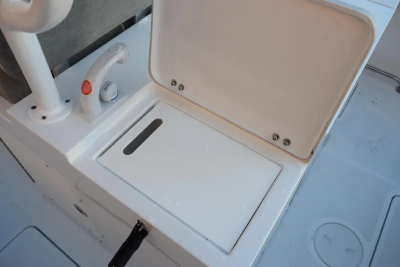 Slide: The Image of 2025 Sea Hunt Gamefish 28 boat storage compartment with open lid and faucet. - 20