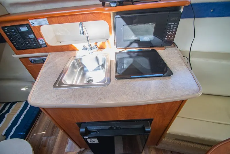 Slide: The Image of Compact kitchen area in a 2010 Bayliner 2450 Ciera boat with sink, microwave, and stove. - 15