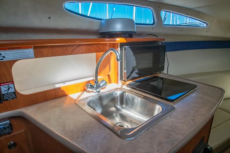 Slide: The Image of Compact kitchen area in a 2010 Bayliner 2450 Ciera boat with sink and microwave. - 16