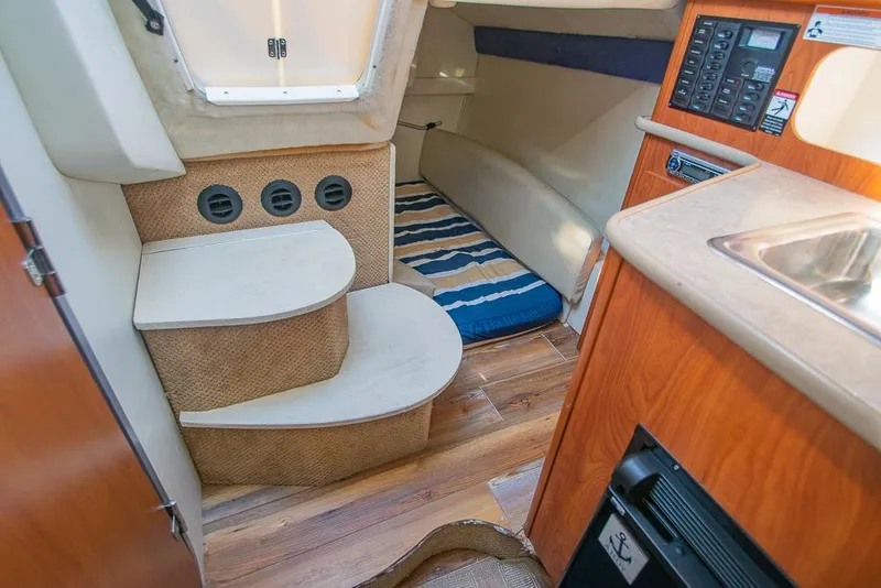 Slide: The Image of Interior of 2010 Bayliner 2450 Ciera boat with cozy cabin and striped bedding. - 20