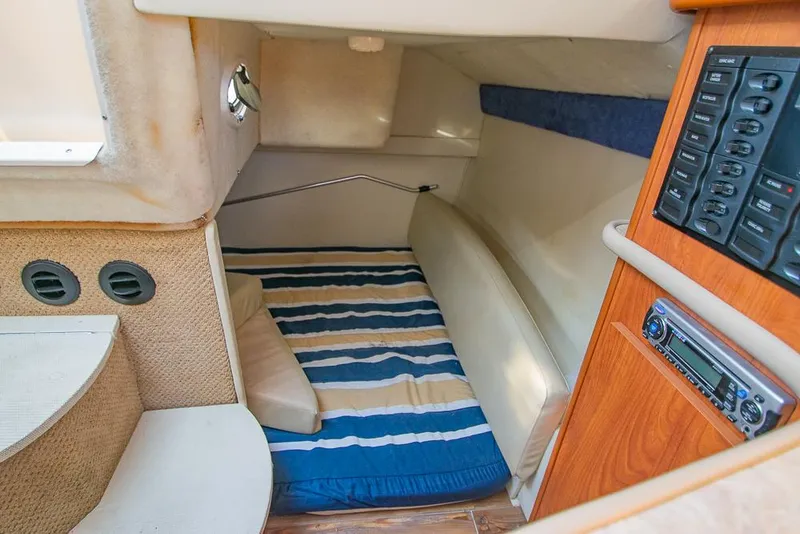 Slide: The Image of Interior cabin of 2010 Bayliner 2450 Ciera with striped bedding and control panel. - 21