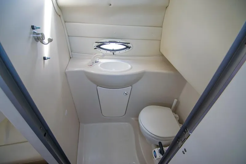Slide: The Image of 2010 Bayliner 2450 Ciera boat bathroom with sink, toilet, and porthole window. - 22
