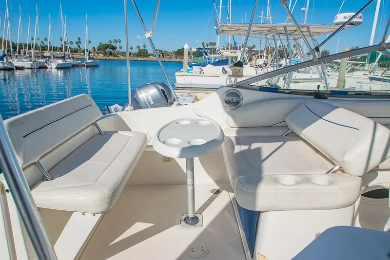 Slide: The Image of Bayliner 2450 Ciera 2010 boat interior with white seating and table, docked in a marina. - 7