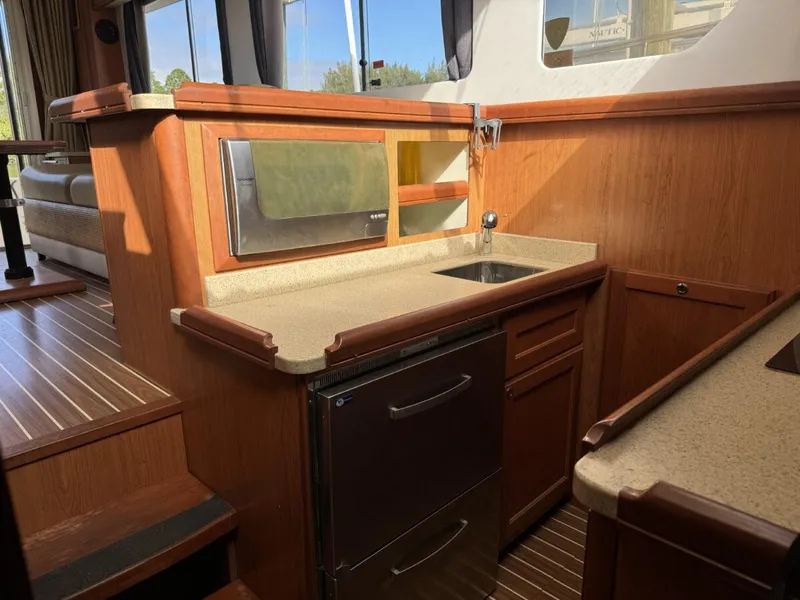 Slide: The Image of 2008 Mainship 34 Trawler Hardtop interior kitchen with wood cabinetry and compact appliances. - 15