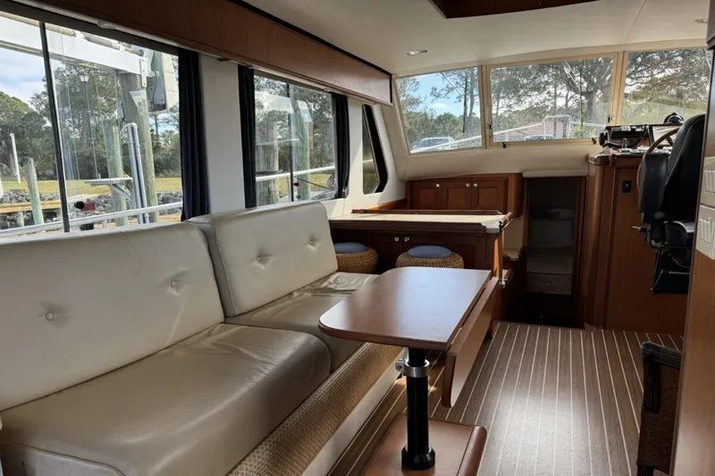Slide: The Image of Interior of 2008 Mainship 34 Trawler Hardtop, featuring a cozy seating area and wooden accents. - 4
