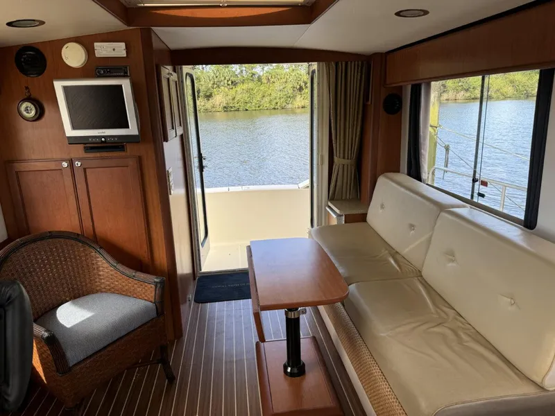 Slide: The Image of 2008 Mainship 34 Trawler Hardtop interior with sofa, table, and water view. - 5