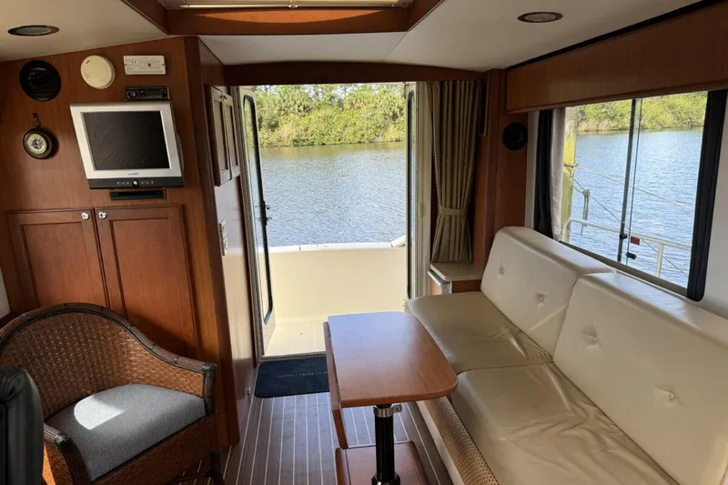 Slide: The Image of Interior of 2008 Mainship 34 Trawler Hardtop with sofa, table, and river view. - 6