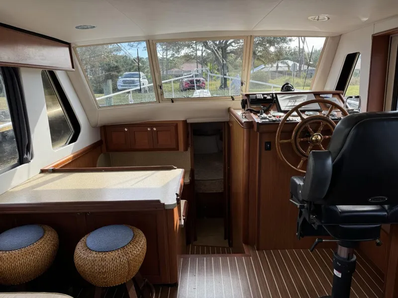 Slide: The Image of 2008 Mainship 34 Trawler Hardtop interior with helm, seating, and wooden accents. - 7