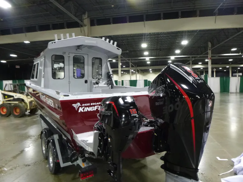 Slide: The Image of 2025 KingFisher 2425 Escape HT boat with dual outboard motors in an indoor setting. - 19