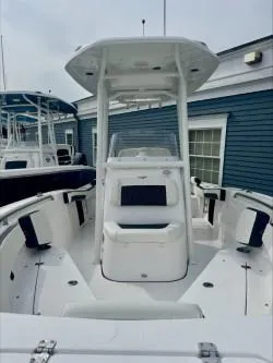 Slide: The Image of 2025 Tidewater 210 LXF boat with T-top, docked near blue building. - 4
