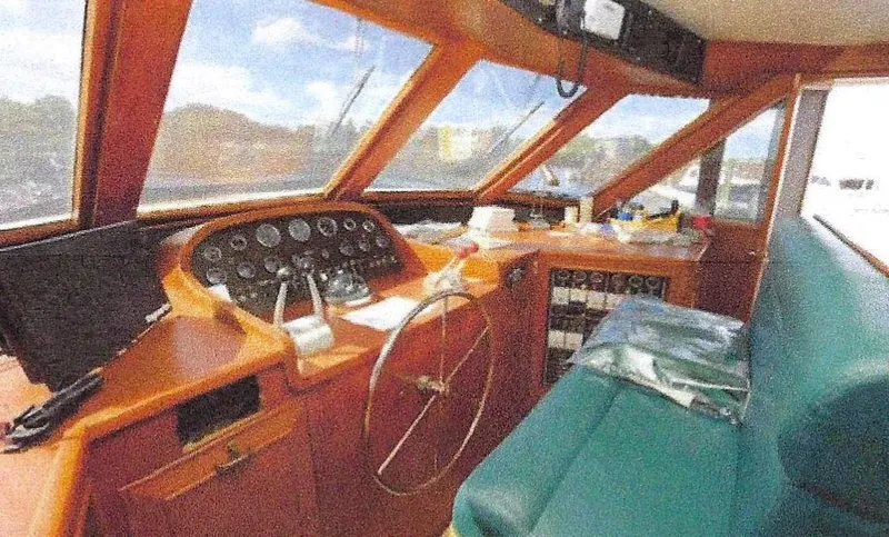 Slide: The Image of 1984 Ocean Alexander Flying Bridge Motor Yacht cockpit with classic wooden dashboard and green seating. - 10