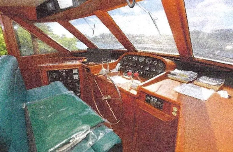 Slide: The Image of 1984 Ocean Alexander Flying Bridge Motor Yacht helm with classic wooden dashboard and green seating. - 11