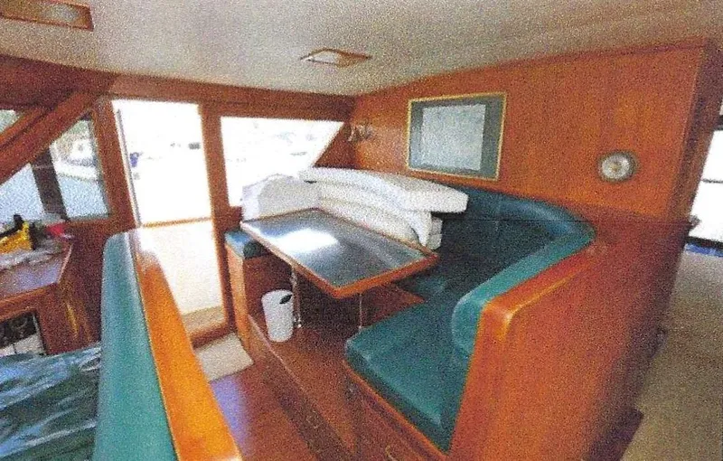 Slide: The Image of 1984 Ocean Alexander Flying Bridge Motor Yacht interior with teal seating and wooden accents. - 13