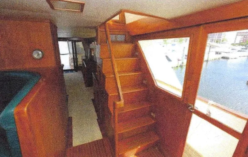 Slide: The Image of 1984 Ocean Alexander Flying Bridge Motor Yacht interior with wooden stairs and waterfront view. - 14