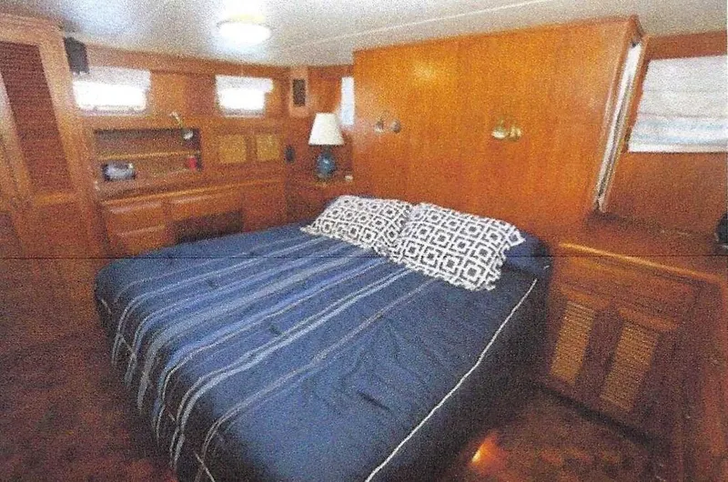 Slide: The Image of 1984 Ocean Alexander Flying Bridge Motor Yacht bedroom with wood paneling and cozy bedding. - 27