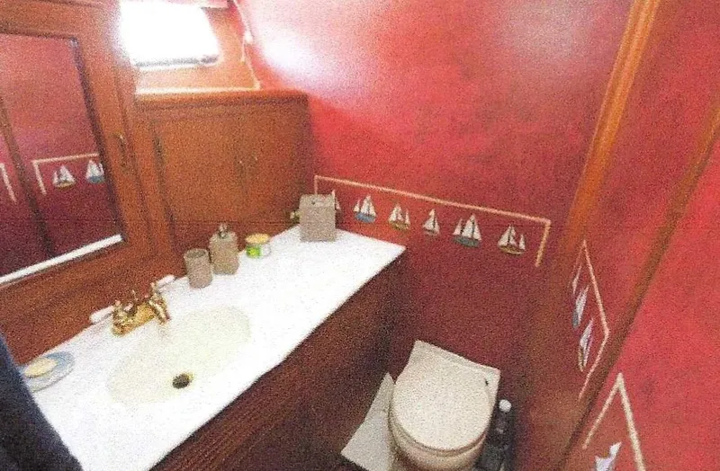 Slide: The Image of 1984 Ocean Alexander yacht bathroom with red walls, nautical decor, sink, and toilet. - 37