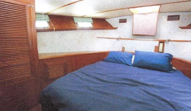 Slide: The Image of 1984 Ocean Alexander Flying Bridge Motor Yacht cabin with bed, wooden interior, and small windows. - 42