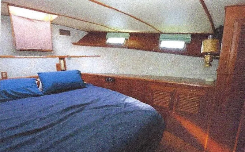 Slide: The Image of 1984 Ocean Alexander Flying Bridge Motor Yacht cabin with bed, wooden cabinetry, and small windows. - 43
