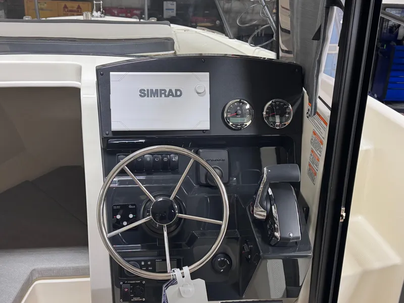 Slide: The Image of 2025 Trophy 25 Pilothouse dashboard with Simrad navigation system and steering wheel. - 12