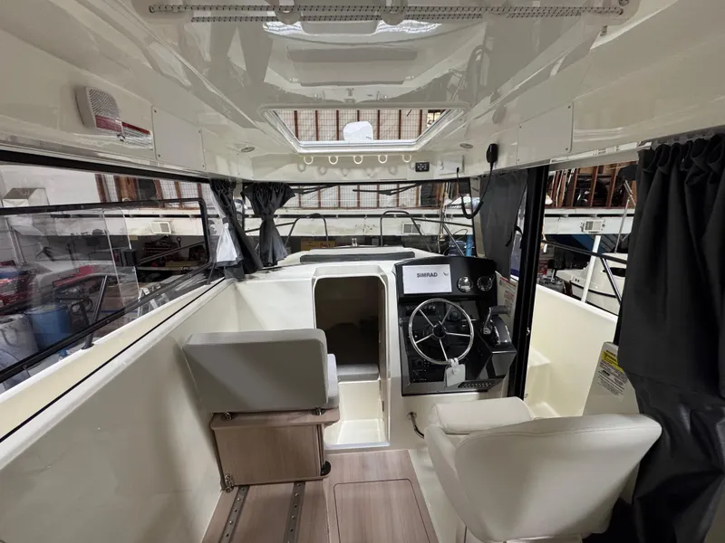 Slide: The Image of Interior of a 2025 Trophy 25 Pilothouse boat, featuring steering wheel and seating. - 13