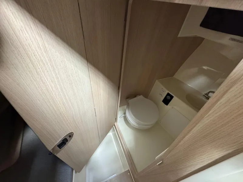 Slide: The Image of 2025 Trophy 25 Pilothouse interior bathroom with compact toilet and wooden finish. - 15