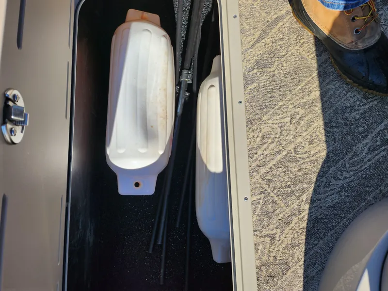 Slide: The Image of Storage compartment in a 2022 JC Neptoon 25 TT DSL boat with white containers. - 12