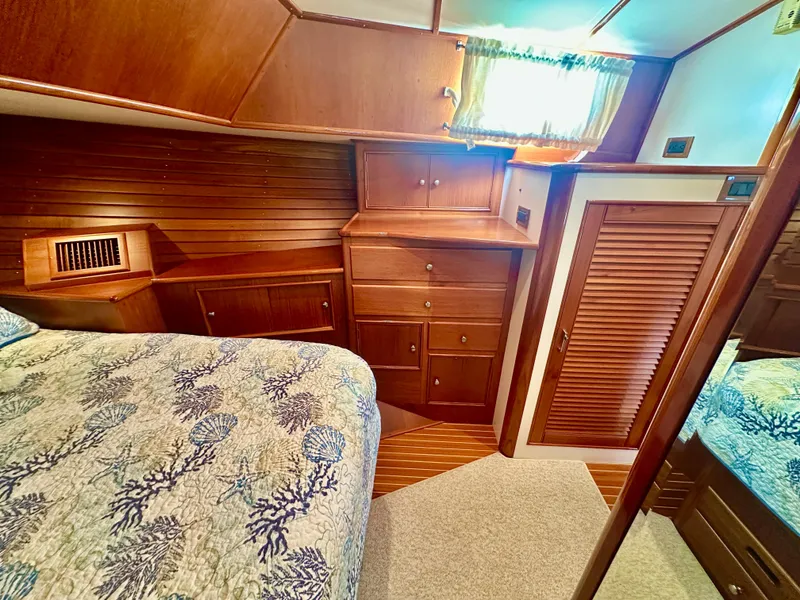 Slide: The Image of 2001 Grand Banks 49 Eastbay HX cabin with wooden cabinetry and patterned bedding. - 30