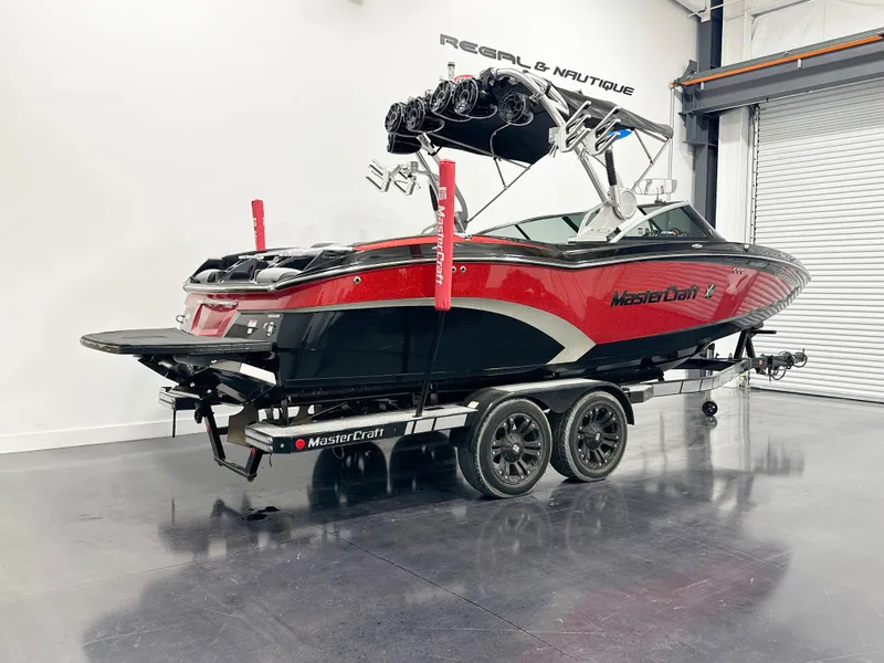 Slide: The Image of 2015 MasterCraft X23 boat on trailer in showroom, red and black design. - 3