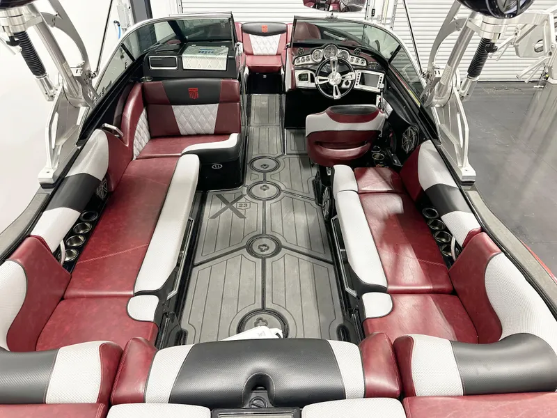 Slide: The Image of 2015 MasterCraft X23 boat interior with red and gray seating, modern dashboard, and spacious layout. - 4