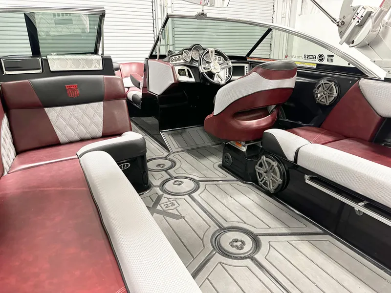Slide: The Image of 2015 MasterCraft X23 boat interior with red and white seating, modern dashboard, and stylish flooring. - 5