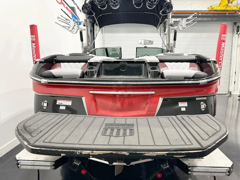 Slide: The Image of 2015 MasterCraft X23 boat, rear view, red and black design, in a showroom. - 9