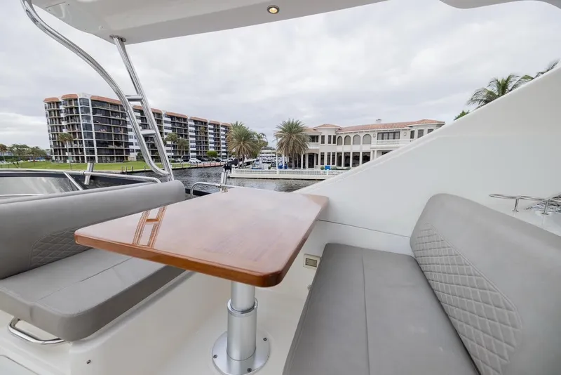 Slide: The Image of 2017 Sea Ray 59 Flybridge yacht with elegant seating and table, overlooking waterfront buildings. - 12