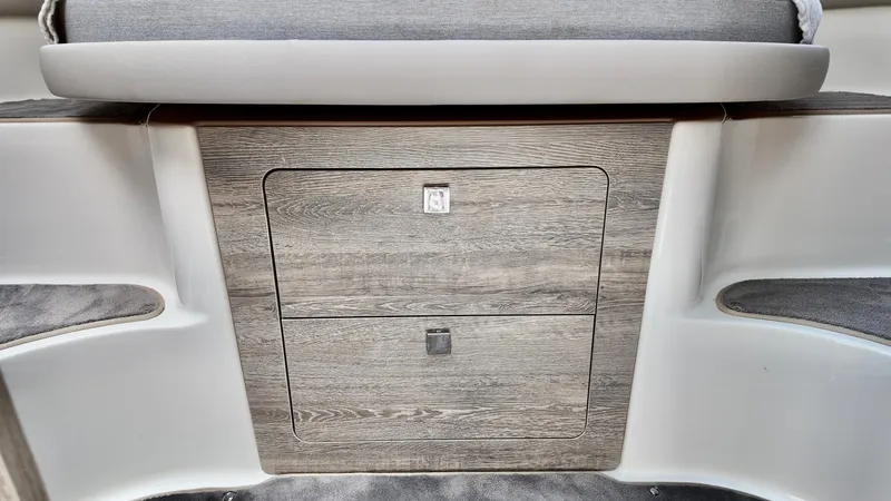 Slide: The Image of 2025 Bayliner Trophy 29 Explorer interior storage compartment with wood finish and cushioned seating. - 11