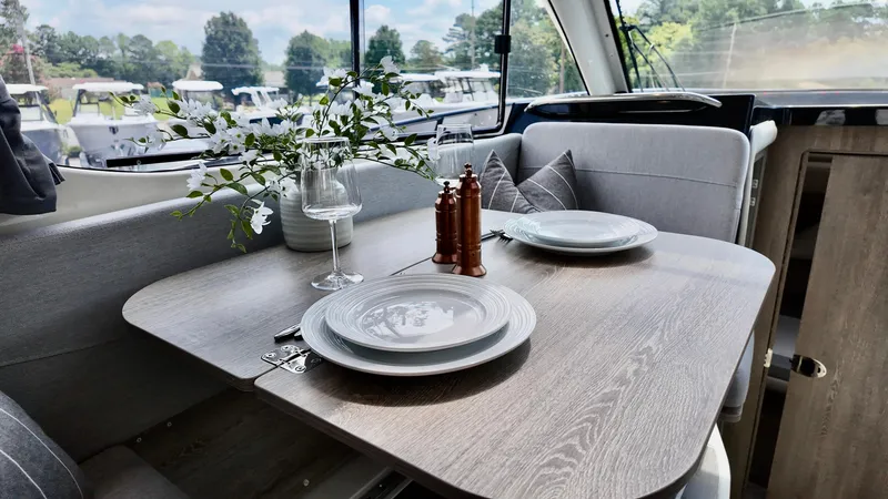 Slide: The Image of Interior of 2025 Bayliner Trophy 29 Explorer with elegant dining setup and scenic window view. - 14