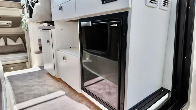 Slide: The Image of 2025 Bayliner Trophy 29 Explorer interior with compact fridge and modern cabinetry. - 32