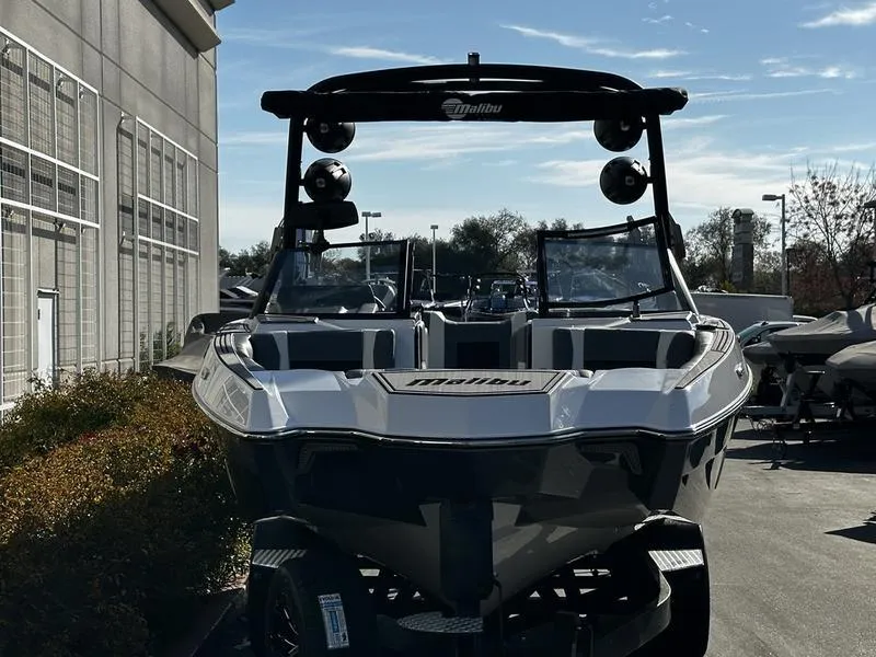 Slide: The Image of 2025 Malibu Wakesetter 24 MXZ boat parked outdoors, front view. - 2