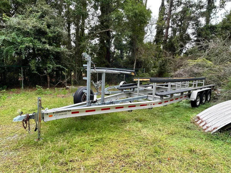 Slide: The Image of Trailer for 2008 World Cat 330 TE boat on grassy area, surrounded by trees. - 31