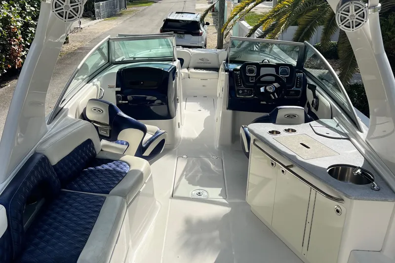 Slide: The Image of 2013 Chaparral 284 Sunesta boat interior with seating and helm, parked on a sunny street. - 4