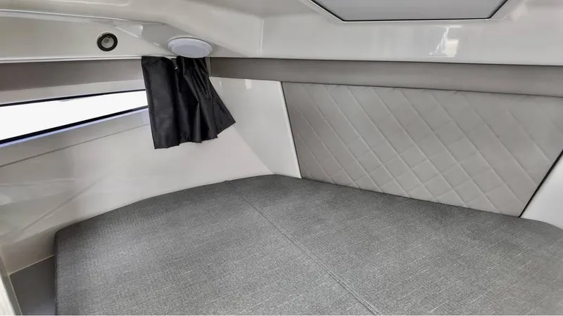 Slide: The Image of 2025 Bayliner TROPHY 25 EXPLORER cabin interior with gray upholstery and window curtain. - 11