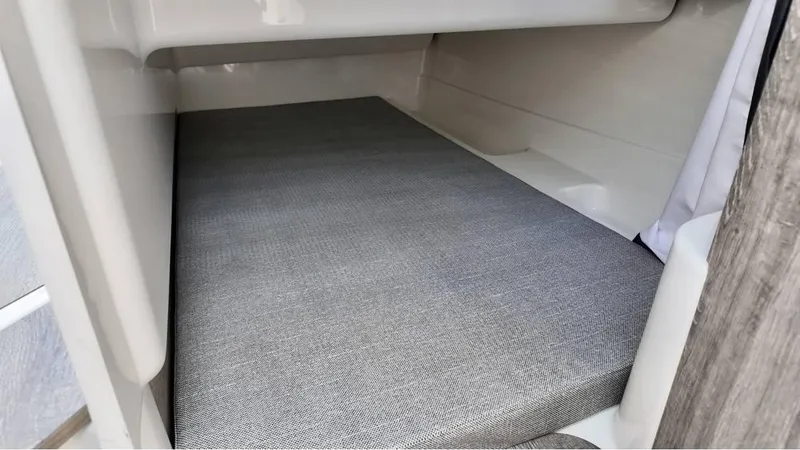 Slide: The Image of 2025 Bayliner TROPHY 25 EXPLORER cabin interior with cushioned sleeping area. - 12