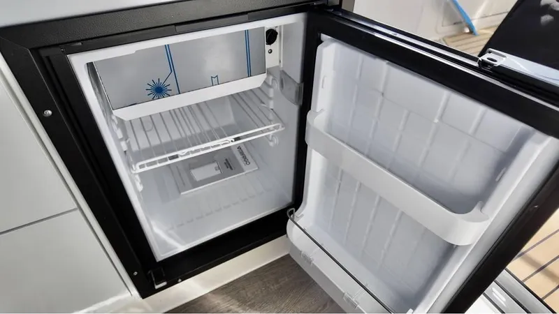Slide: The Image of Open refrigerator inside 2025 Bayliner TROPHY 25 EXPLORER boat, showcasing interior storage space. - 19