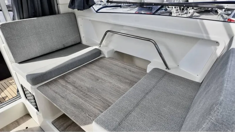 Slide: The Image of Interior seating of 2025 Bayliner TROPHY 25 EXPLORER with gray cushions and wooden table. - 21