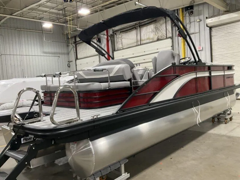 Slide: The Image of 2025 Bennington 24 SXSB pontoon boat in a warehouse, featuring sleek design and modern seating. - 11