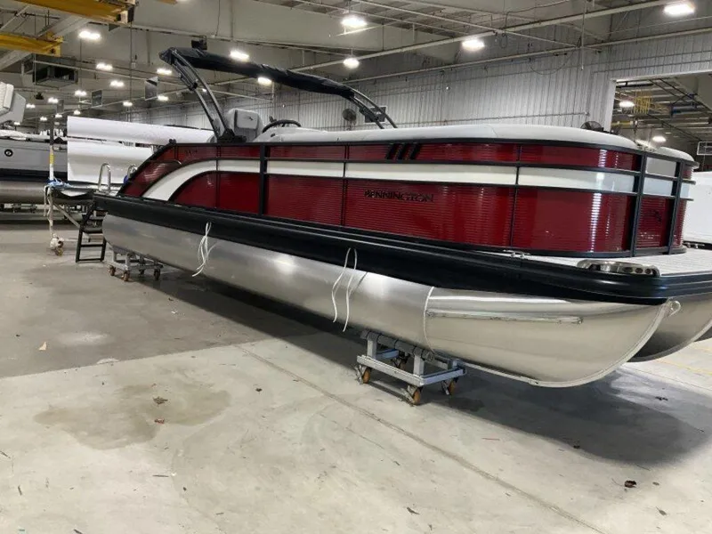 Slide: The Image of 2025 Bennington 24 SXSB pontoon boat in a warehouse, featuring sleek red and silver design. - 12