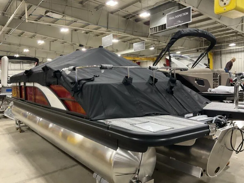 Slide: The Image of 2025 Bennington 24 SXSB pontoon boat covered in a showroom, showcasing sleek design and modern features. - 18